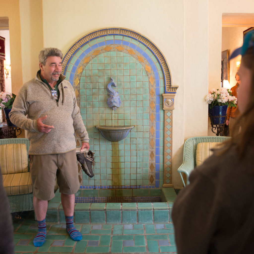 Tantsits takes the group to the sun room, where the Phillips family would relax by the fountain and enjoy the natural light coming through the windows. He points out some points of interest, like the indoor fountain with gold leaf details.