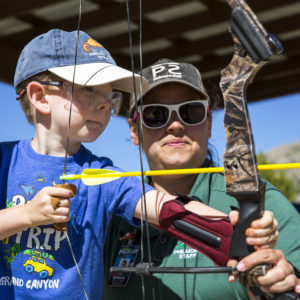 Brittany Childers, a second year program counselor, instructs 5 year old Gus Bower, a member of the Bandits group, on how to shoot a bow and arrow at a target over 10 feet away