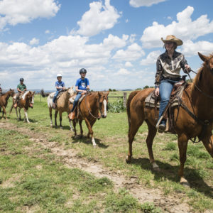 Wrangler Becca Atherton leads a group of sidewinders out of Cattle Headquarters during a horseback ride on July 17, 2017.