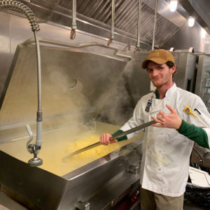 Graham M. cooks scrambled eggs in the dump skillet at the CHQ dioning hall