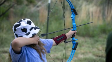 A young participant takes aim with a bow and arrow on July 27, 2023 in Cimarron, NM
