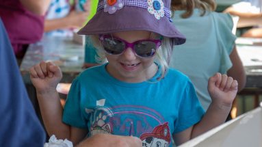 A father and grandfather help a girl paint a flower at the Philmont Training Center craft center at Philmont Scout Ranch in Cimarron, New Mexico on Monday, July 29. 2019.